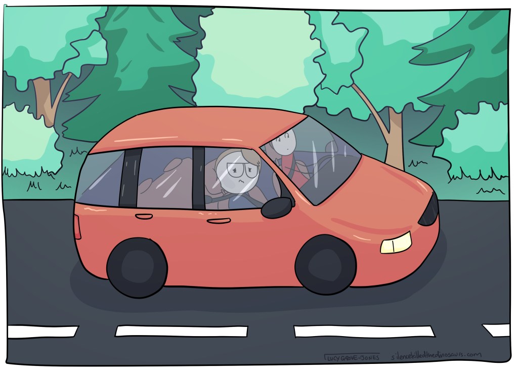 The car with me and my partner in it. We are driving on a road through a wooded area.